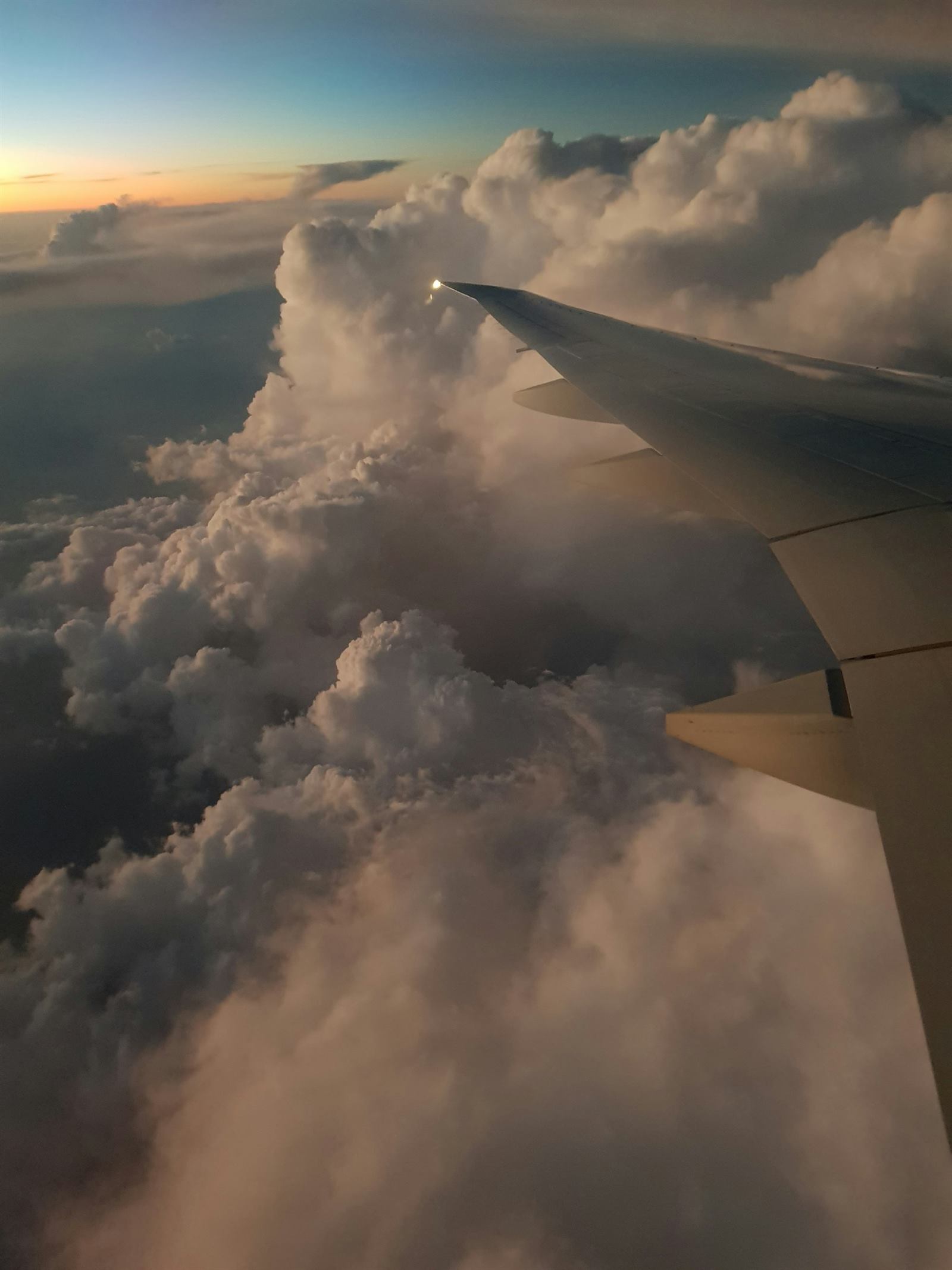 Airplane wing above clouds at sunset